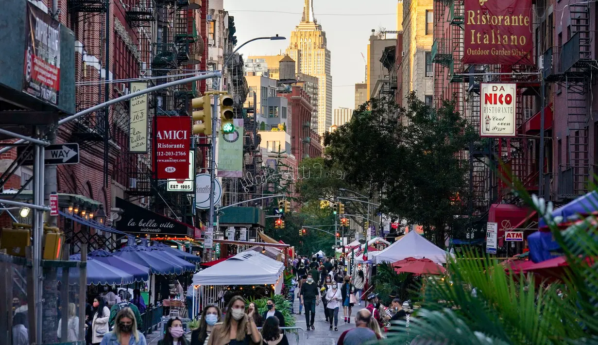 Orang-orang berjalan melalui restoran yang mengoperasikan area luar ruangan (outdoor) hingga ke trotoar dan jalanan di New York, 3 Oktober 2020. Kota itu mengizinkan restoran membuat area makan outdoor sebagai upaya mengatasi dampak ekonomi COVID-19 yang berkelanjutan. (AP Photo/John Minchillo)
