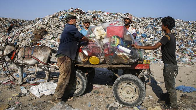 Pengumpul sampah Palestina memuat jeriken ke gerobak keledai di tempat pembuangan sampah di Kota Gaza (29/7/2019). Kemiskinan yang terjadi akibat blokade Israel dan kurangnya kesempatan kerja membuat beberapa warga Palestina memilih bekerja mencari sampah untuk dijual. (AFP Photo/Mohammed)