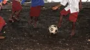 Dengan seragam sekolah Merah-Putih menempel dibadan, Anak-anak di Alor bermain bola dekat pantai, mereka menikmati waktu pulang sekolah dengan bermain bersama. (Bola.com/Nicklas Hanoatubun)