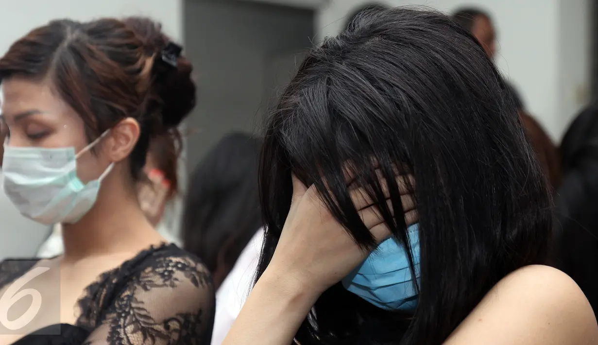 Seorang perempuan WNA menutup wajahnya saat diamankan di Kantor Imigrasi Kelas I Khusus Jakarta Barat, Sabtu (7/1). Mereka diduga melanggar keimigrasian yang berprofesi sebagai penari, pemandu lagu, Pekerja Seks Komersil (PSK). (Liputan6.com/Johan Tallo)