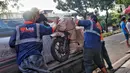 Pekerja tengah mengepak sepeda motor yang akan dikirim melalui jasa pengiriman dengan kereta api di Kawasan Stasiun Senen, Jakarta, Kamis (13/4/2023).(Liputan6.com/Angga Yuniar)