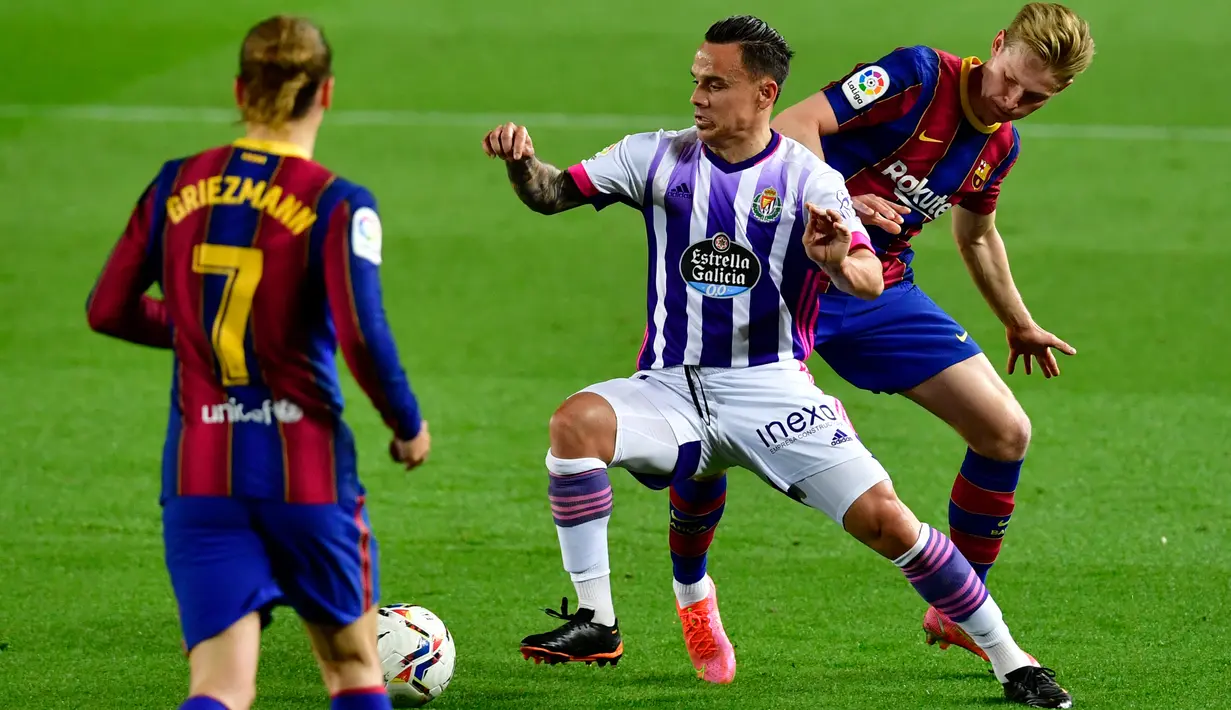 Gelandang Barcelona Frenkie De Jong (kanan) dan Antoine Griezmann bersaing dengan gelandang Real Valladolid, Roque Mesa (tengah) pada pekan ke-29 Liga Spanyol di Camp Nou, Selasa (6/4/2021) dini hari WIB. Barcelona susah payah menang tipis 1-0 berkat gol Ousmane Dembele. (Pau BARRENA/AFP)