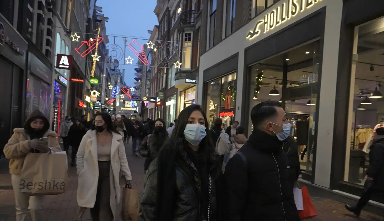 Orang-orang melintasi jalan di Amsterdam, Belanda, Sabtu (18/12/2021). Pemerintah Belanda akan melakukan penguncian ketat atau lockdown selama periode Natal dan Tahun Baru untuk mencoba menahan varian covid-19 Omicron yang sangat menular. (AP Photo/Peter Dejong)