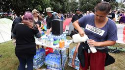 Relawan memasukkan susu ke dalam botol jika terjadi semprotan merica di halaman parlemen pada hari ketiga demonstrasi menentang pembatasan Covid-19, terinspirasi oleh demonstrasi serupa di Kanada, di Wellington (10/2/2022). (AFP/Marty Melville)