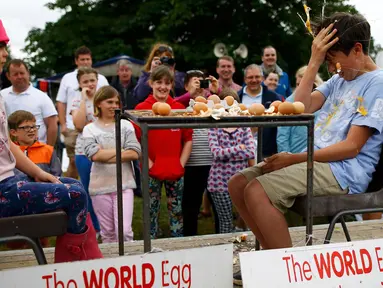 Seorang anak laki-laki memecahkan telur dikepalanya usai kalah dalam permainan Russian Egg Roulette pada acara Kompetisi Melempar Telur Dunia dan Vintage Day di Swaton, Inggris, Minggu (28/6/2015). (REUTERS/Darren Staples)