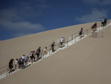 Orang-orang menaiki tangga di Dune du Pilat, bukit pasir tertinggi di Eropa, pada hari pembukaannya kembali setelah kebakaran hebat menghancurkan 7000 hektar hutan La Teste-de-Buch di dekatnya, di Pyla sur Mer , di Gironde, barat daya Prancis (27/7/2022). (AFP/Romain Perrocheau)