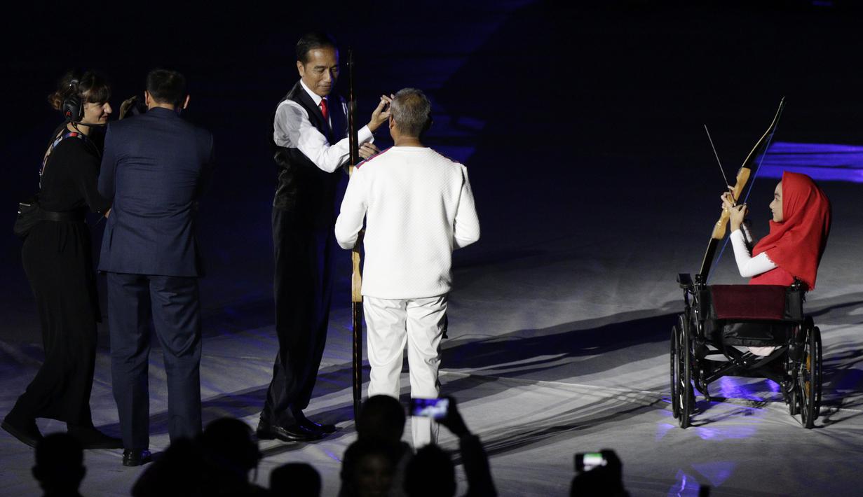 Presiden Indonesia, Joko Widodo, bersama penyandang disabilitas memanah tugu saat pembukaan Asian Para Games di SUGBK, Jakarta, Sabtu (06/10/2018). Acara tersebut dimeriahkan dengan aksi para penyandang disabilitas. (Bola.com/M Iqbal Ichsan)