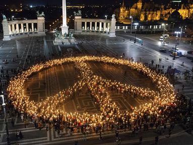 Orang-orang membuat tanda perdamaian dengan lampu saat demonstrasi untuk Ukraina yang diselenggarakan oleh Greenpeace di Heroes Square, Budapest, Hungaria, 9 Maret 2022. Invasi Rusia ke Ukraina telah memicu migrasi massal terbesar di Eropa dalam beberapa dekade. (AP Photo/Anna Szilagyi)
