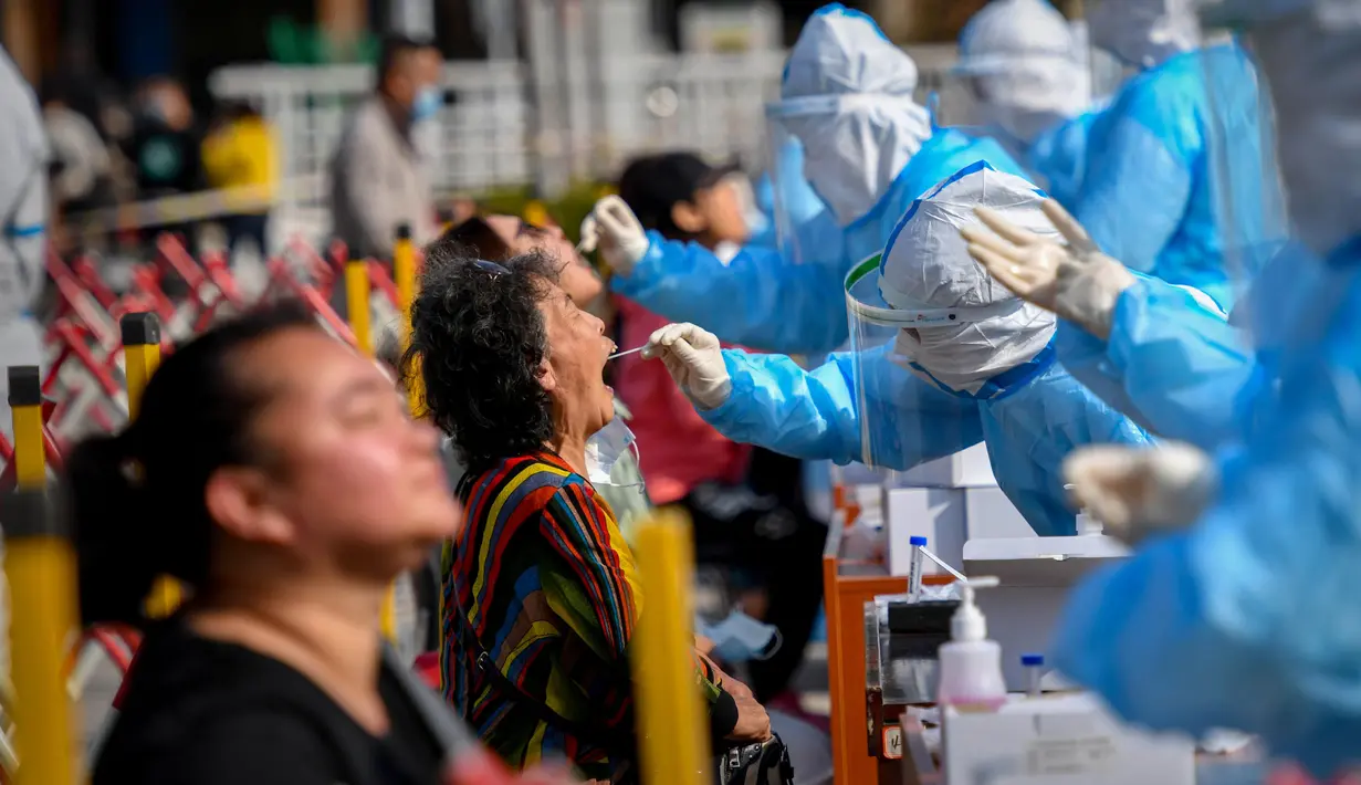Petugas medis mengambil sampel warga saat tes COVID-19 di Qingdao, China, Senin (12/10/2020). Lebih dari 9 juta orang yang tinggal di kota Qingdao menjalani tes COVID-19 secara massal setelah kasus baru muncul terkait dengan rumah sakit yang merawat pasien terinfeksi dari luar negeri. (STR/AFP)