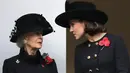 Kate Middleton berbincang dengan Putri Alexandra, Yang Terhormat Lady Ogilvy, pada upacara Remembrance Sunday Service di London, Minggu (12/11). Kate terlihat cantik dalam balutan velvet dress coat hitam dengan aksen kancing ganda. (TOLGA AKMEN / AFP)