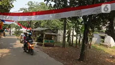 Warga melintasi umbul-umbul dari tas sembako bantuan Presiden Joko Widodo di Jalan Caringin, Bedahan Barat, Sawangan, Depok, Jawa Barat, Jumat (7/8/2020). Bahan tas sembako berwarna merah putih tersebut disulap menjadi umbul-umbul sepanjang 500 meter. (Liputan6.com/Herman Zakharia)