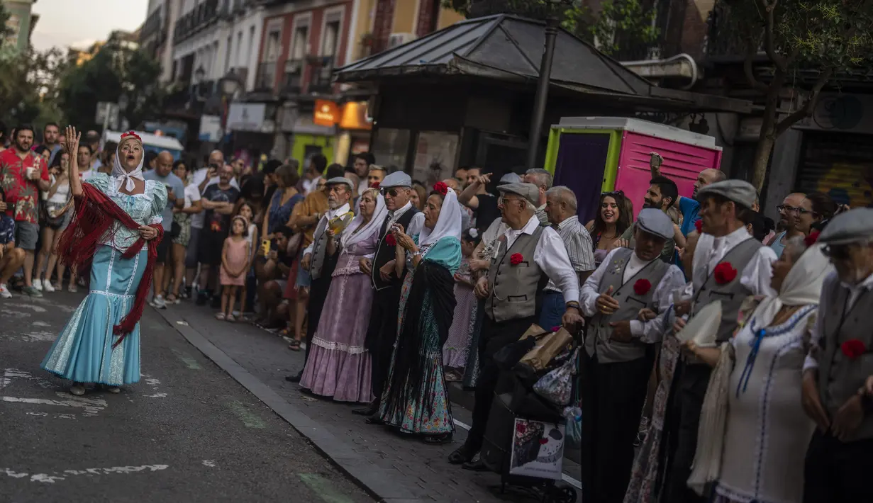 Orang-orang yang mengenakan pakaian tradisional 'chulapo' menari selama perayaan San Cayetano, santo pelindung tenaga kerja dan roti, di lingkungan Lavapies di Madrid, Spanyol, Sabtu (6/8/2022). Festival San Cayetano menandai awal dari serangkaian festival populer di Madrid. (AP Photo/Manu Fernandez)