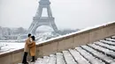 Pasangan berpose di depan Menara Eiffel di Paris, Prancis (7/2). Hujan salju yang sangat lebat membuat transportasi umum di paruh utara Prancis dan di Paris tidak dapat beroperasi. (AP Photo / Thibault Camus)