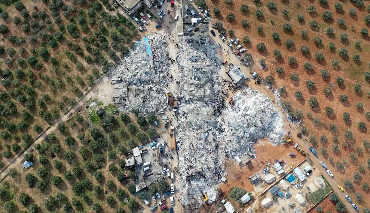 <p>Pemandangan dari udara ini menunjukkan penduduk mencari korban dan penyintas di tengah puing-puing bangunan yang runtuh setelah gempa bumi di desa Besnia dekat Harim, di provinsi Idlib barat laut yang dikuasai pemberontak Suriah di perbatasan dengan Turki,&nbsp;Senin (6/2/2023). Gempa itu menghancurkan Kastil Gaziantep yang bersejarah dan banyak bangunan bersejarah lainnya di daerah itu. (Omar HAJ KADOUR / AFP)</p>