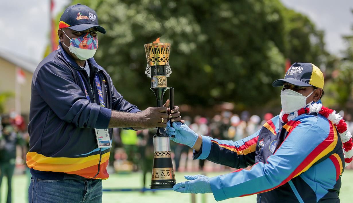 Bupati Merauke Romanus Mbaraka (kiri) menerima penyerahan Api PON XX Papua dari pembawa Api PON Egelberta Kaize yang merupakan atlet bola voli pantai berprestasi asal Papua di Halaman Kantor Bupati Merauke, Papua, Rabu 30 September 2021. (FOTO PB PON XX PAPUA/Ali Lutfi)