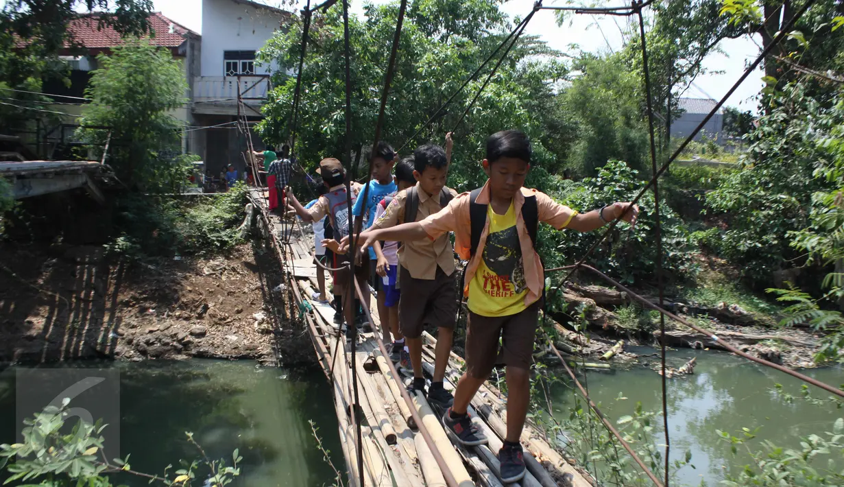Sejumlah pelajar melintasi Kali Angke menggunakan jembatan rapuh di Kampung Cantiga, Petir, Cipondoh, Tangerang, Rabu (2/9/2015). Jembatan berusia lima tahun tersebut menghubungkan Cipondoh dan Kembangan, Jakarta. (Liputan6.com/Gempur M Surya)