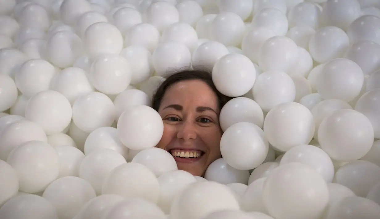 Seorang wanita tersenyum saat tenggelam dalam kolam bola putih di kantor SoHo, New York City, Selasa (25/8/2015). Tempat ini dibuat agar para karyawan dapat bermain dan dapat menhasilkan sesuatu yang kreatif. (REUTERS/Mike Segar)