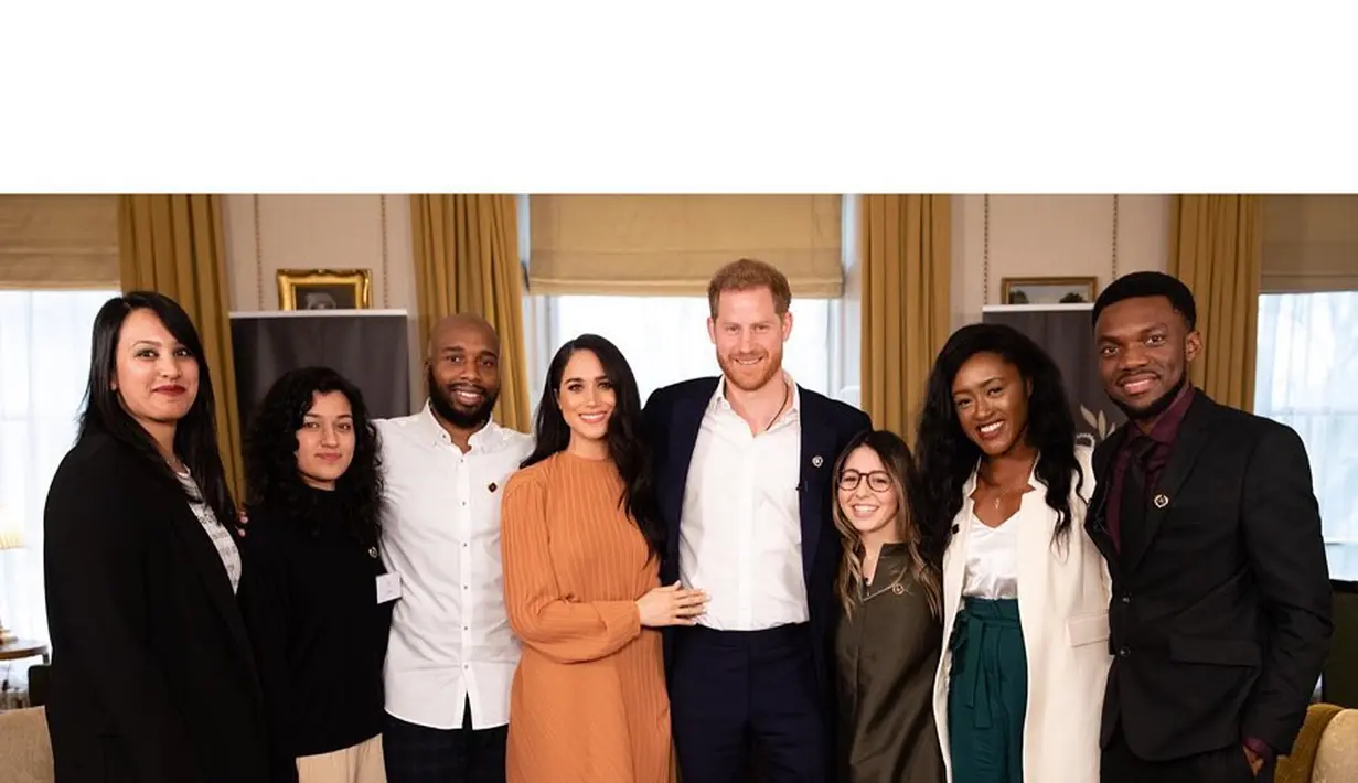 Meghan Markle bersama dengan sang suami, Pangeran Harry berpose bersama beberapa orang, mengenakan sebuah dress simpel berwarna cokelat. [Foto: Instagram/sussexroyal]