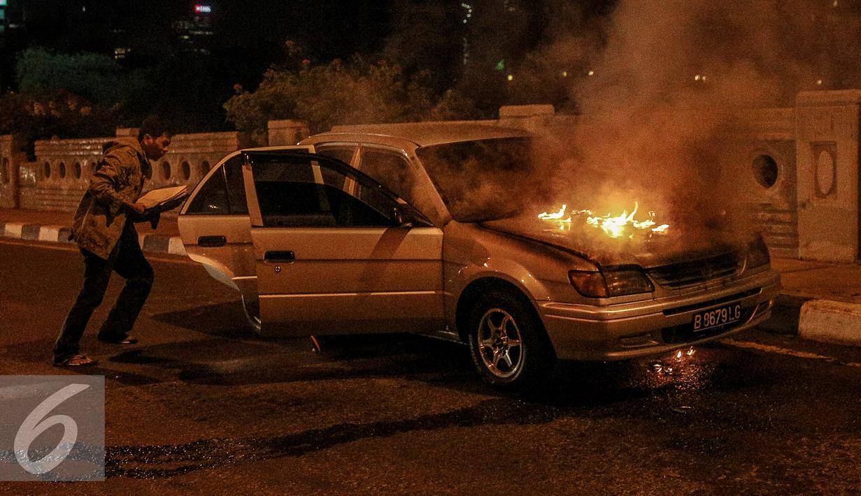 Pemilik mobil berusaha menyelamatkan barang miliknya saat mobil terbakar di jalan layang Latuharhari, Jakarta, Kamis (18/9/2015). Diduga kebakaran akibat konsleting listrik yang terjadi dibagian depan kap mobil. (Liputan6.com/Faizal Fanani)