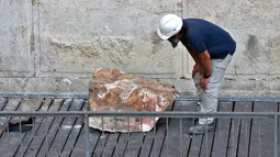 Pekerja Otoritas Pengurus Benda Antik Israel memeriksa batu besar yang jatuh dari Tembok Ratapan di Kota Tua Yerusalem, Rabu (25/7). Rabbi Tembok Ratapan menyebut kejadian ini langka dan belum pernah muncul dalam berpuluh-puluh tahun. (AFP/AHMAD GHARABLI)
