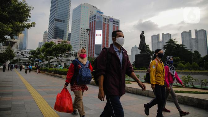 Pekerja berjalan usai bekerja perkantoran di kawasan Jalan Jenderal Sudirman, Jakarta, Kamis (16/4/2020). Pemprov DKI Jakarta akan memberikan saksi berupa mencabut perizinan perusahaan yang tetap beroperasi di masa PSBB kecuali delapan sektor yang memang diizinkan. (Liputan6.com/Faizal Fanani)