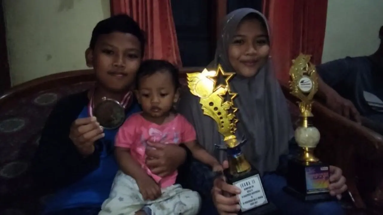 Anak Sukari dari kanan J mengajak adiknya paling kecil  N, Kemudian V  menunjukan medali dan tropi piala yang diperolehnya selama ini. (Istimewa)