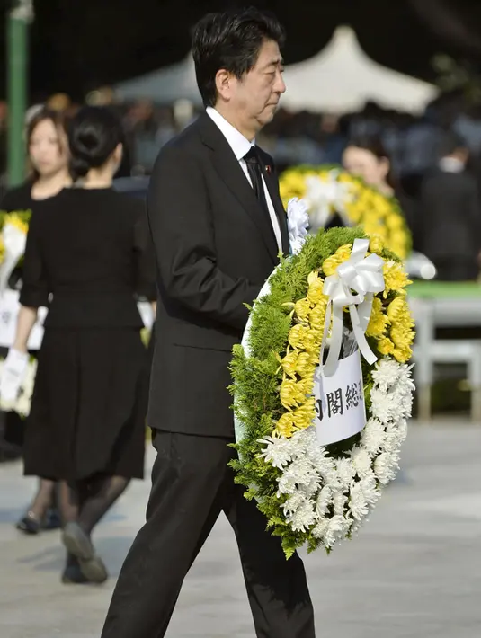 Perdana Menteri Jepang Shinzo Abe membawa karangan bunga pada saat upacara peringatan 70 tahun jatuhnya bom atom di Hiroshima, Jepang (6/8/2015). 140.000 penduduk Jepang tewas akibat Bom Atom. (REUTERS/Kyodo)