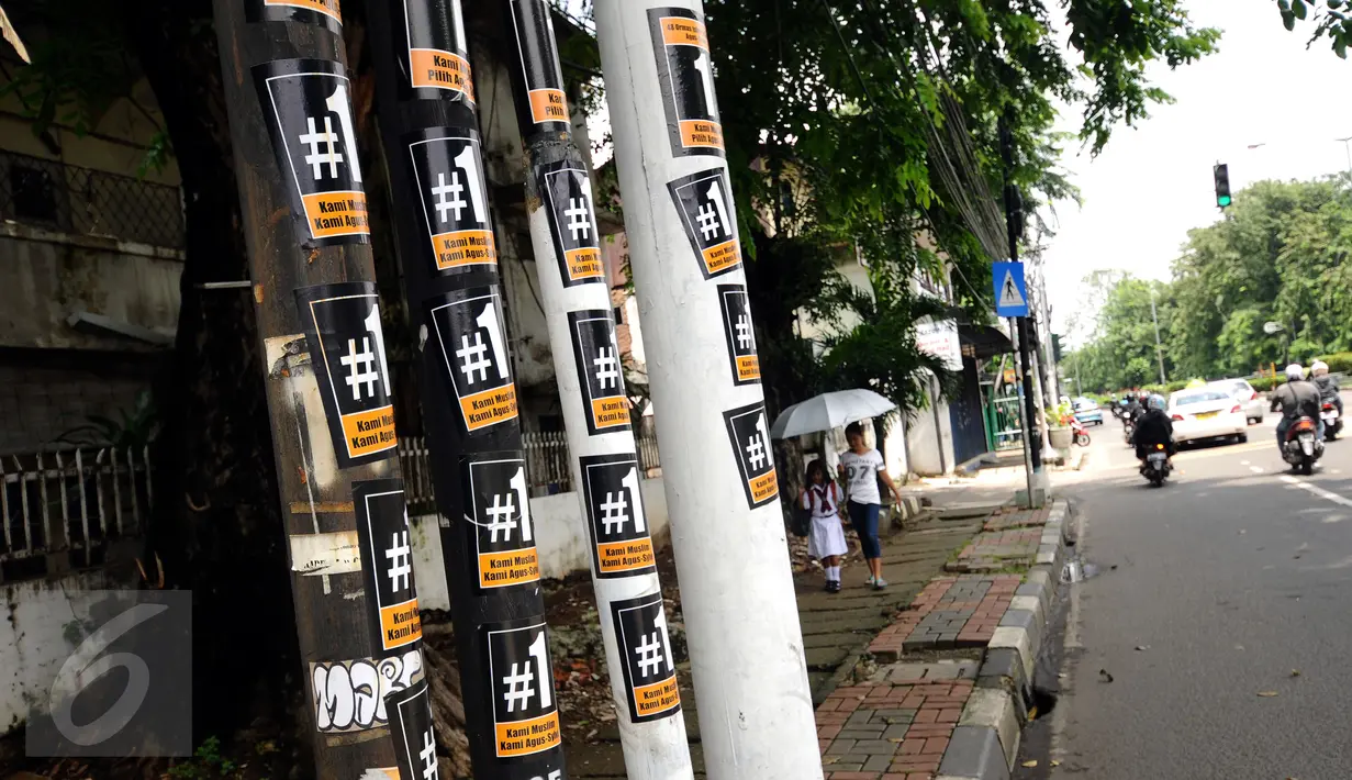 Stiker bergambar #1 masih menempel di beberapa tiang di sekitar Jalan Otista Raya, Jakarta, Senin (13/1). Hingga H-2 Pilkada DKI Jakarta, alat peraga kampanye masih terlihat di beberapa ruas jalan Ibukota. (Liputan6.com/Helmi Fithriansyah)