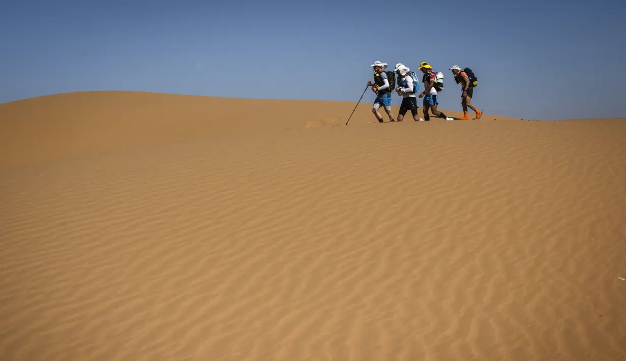Para peserta menyusuri gurun saat mengikuti lomba lari Marathon des Sables ke-34 tahap kedua di Gurun Sahara, Maroko, Senin (8/4). Dalam lomba ini peserta akan diuji batas ketahanan tubuh mereka. (JEAN-PHILIPPE KSIAZEK/AFP)