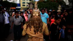 Seorang kontestan beraksi saat mengikuti kontes patung di pusat kota San Salvador , El Salvador, (18/6). Kontes ini menjadi tontonan warga El Savador yang sedang melintas. (REUTERS / Jose Cabezas)