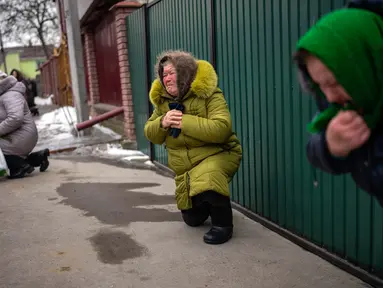 Para pelayat berlutut menunggu peti mati Oleksandr Maksymenko (38) lewat saat pemakamannya di kampung halamannya di Kniazhychi, sebelah timur Kyiv, Ukraina, 13 Februari 2023. Oleksandr Maksymenko, seorang warga sipil yang menjadi sukarelawan di angkatan bersenjata Ukraina, tewas dalam pertempuran di daerah Bakhmut. (AP Photo/Emilio Morenatti)