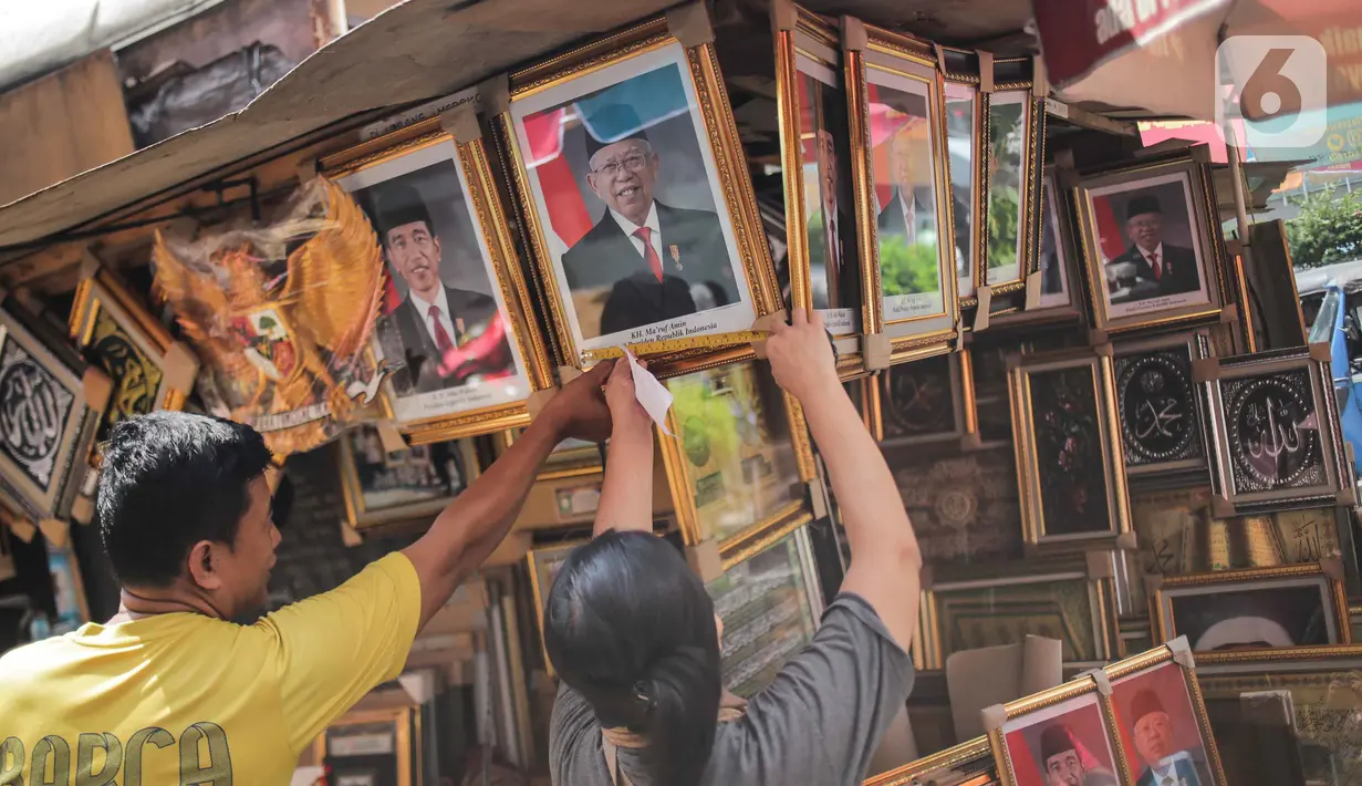 Pedagang melayani pembeli bingkai foto Presiden Jokowi dan Wakil Presiden terpilih Ma'ruf Amin yang dijualnya di Pasar Baru, Jakarta, Rabu (16/10/2019). Menjelang pelantikan presiden, foto pasangan Jokowi-Ma'ruf Amin mulaih dijual ke pasar umum. (Liputan6.com/Faizal Fanani)