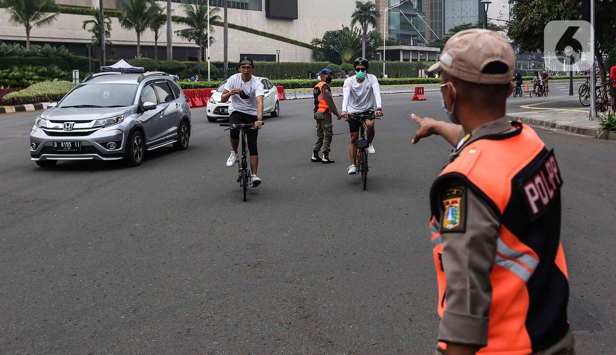Satpol PP menegur pesepeda yang tidak mengenakan masker dengan benar saat melintas di kawasan Bundaran HI, Jakarta, Minggu (17/1/2021). Sosialisasi penggunaan masker untuk mencegah penularan virus corona COVID-19 masih saja diabaikan karena rendahnya kesadaran masyarakat. (Liputan6.com/Johan Tallo)