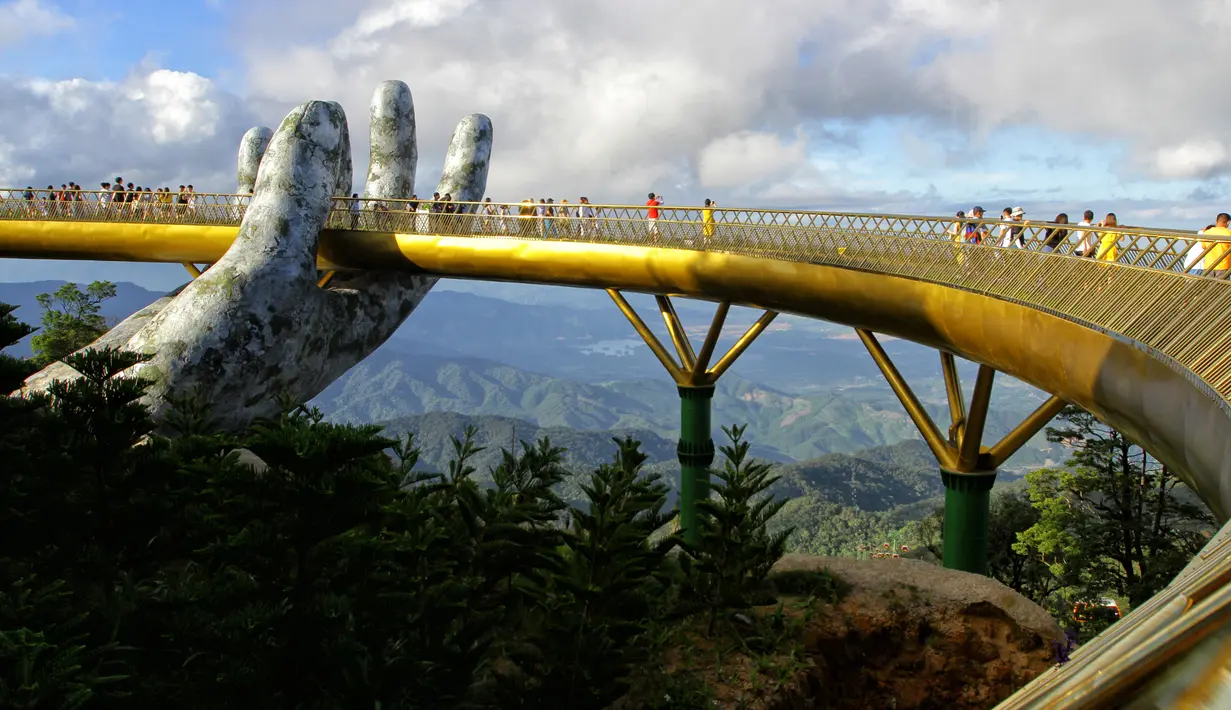 Pengunjung berjalan di sepanjang Golden Bridge di Perbukitan Ba Na dekat Danang, Vietnam, Selasa (31/7). Perancang Golden Bridge mengaku bangga karena rancangannya viral ke seluruh dunia. (Linh PHAM/AFP)