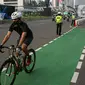 Pesepeda melewati polisi yang melakukan penertiban di kawasan Sudirman-Thamrin, Jakarta Pusat, Rabu (2/6/2021). Wakil Gubernur DKI Jakarta Ahmad Riza Patria mengatakan, sepeda road bike diperbolehkan untuk melintas di Jalan Sudirman-Thamrin pada hari kerja Senin-Jumat. (Liputan6.com/Faizal Fanani)