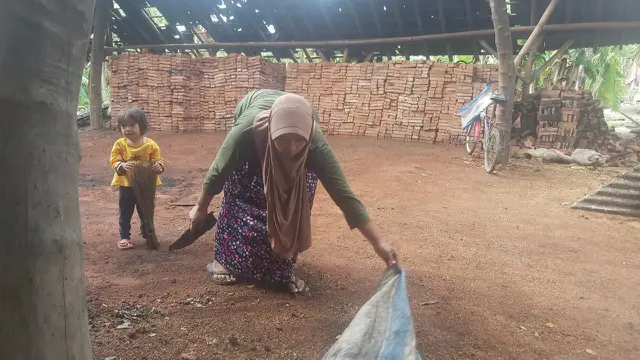 Pengrajin batu bata selamatkan batu bata ditemani anaknya yang masih balita membersihkan lingga rumah pembakaran batu bata. (Foto: Liputan6.com/Felek Wahyu)