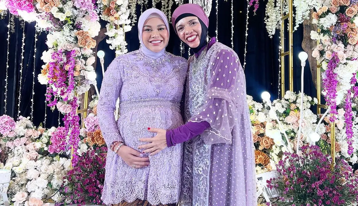 Geni Faruk juga tampil dengan gamis ungu yang cantik. Geni memilih inner ungu polos yang kemudian disempurnakan dengan outer transparan berbordir floral yang tak kalah cantik. Geni Faruk memadukan penampilannya dengan hijab ungu yang serasi. [Foto: Instagram/attahalilintar]