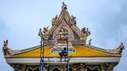 Pekerja meletakkan sentuhan terakhir pada atap Kuil Buddha Wat Pariwat atau Kuil David Beckham di Bangkok, Thailand, Selasa (14/7/2020). Kuil David Beckham dihiasi dengan patung-patung superhero, karakter komik, makhluk mitos dan imajiner, serta tokoh dunia. (Mladen ANTONOV/AFP)
