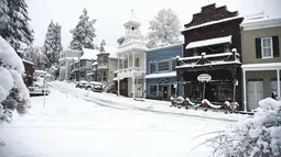 Jalanan utama yang dipenuhi salju pada Senin pagi di Nevada City, California (27/12/2021). Hujan salju dingin membuat perjalanan hampir tidak mungkin dilakukan di beberapa bagian California, Nevada. (Elias Funez/The Union via AP)