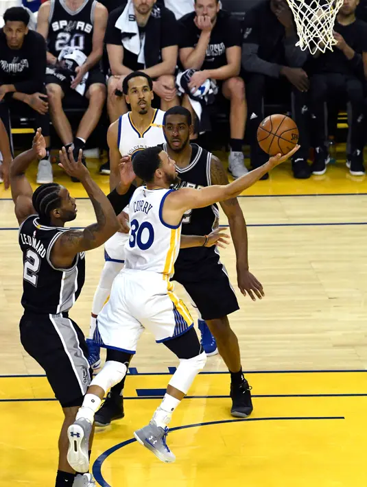 Pemain Warriors, Stephen Curry (30) berusaha memasukan bola dari kawalan LaMarcus Aldridge (12) saat bertanding pada gim pertama final Wilayah Barat playoffs NBA 2017 di Oakland, California (14/5). (Thearon W. Henderson/Getty Images/AFP)