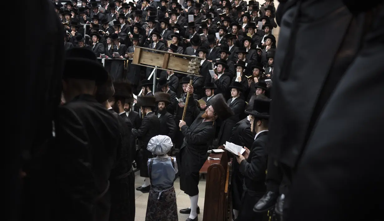 Pria dan anak-anak Yahudi ultra-Ortodoks, beberapa mengenakan kostum membaca Kitab Ester, yang menceritakan kisah festival Yahudi Purim, di sebuah sinagoga di Bnei Brak, Israel, Senin (6/3/2023). Purim dirayakan tiap tahun menurut kalender Ibrani oleh kaum Yahudi. (AP Photo/Oded Balilty)