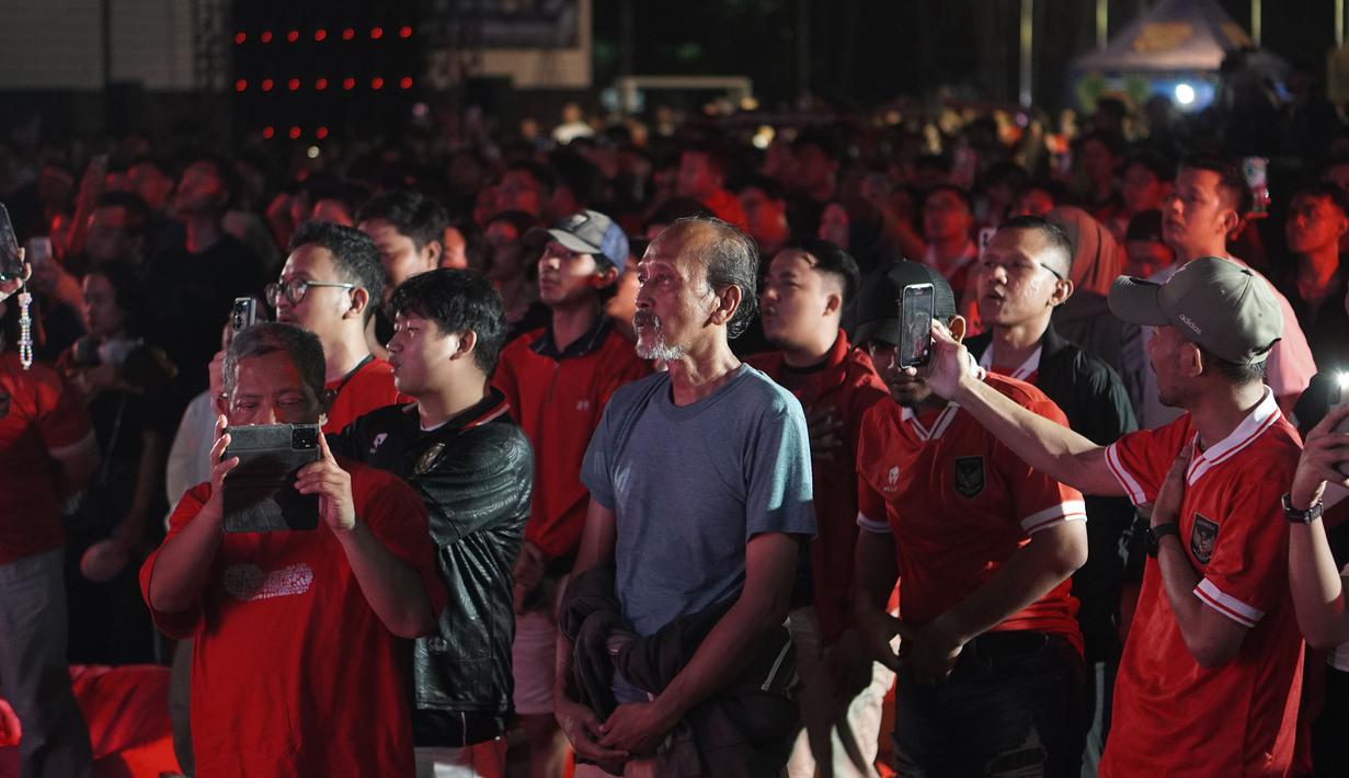 Para suporter Indonesia ikut berdiri menyanyikan lagu kebangsaan Indonesia Raya saat acara nonton bareng laga perebutan tempat ketiga Piala Asia U-23 2024 antara Timnas Indonesia U-23 menghadapi Irak di Plaza Kemenpora, Senayan, Jakarta Pusat, Kamis (2/5/2024) malam WIB. (Bola.com/Afi)