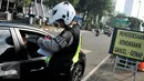 Petugas menilang pengendara mobil berpelat genap yang melintas pada tanggal ganjil di Bundaran Senayan, Jakarta, Rabu (31/8). Sejak kemarin mulai diberlakukan sanksi kepada pengendara yang melanggar aturan ganjil-genap. (Liputan6.com/Gempur M Surya)