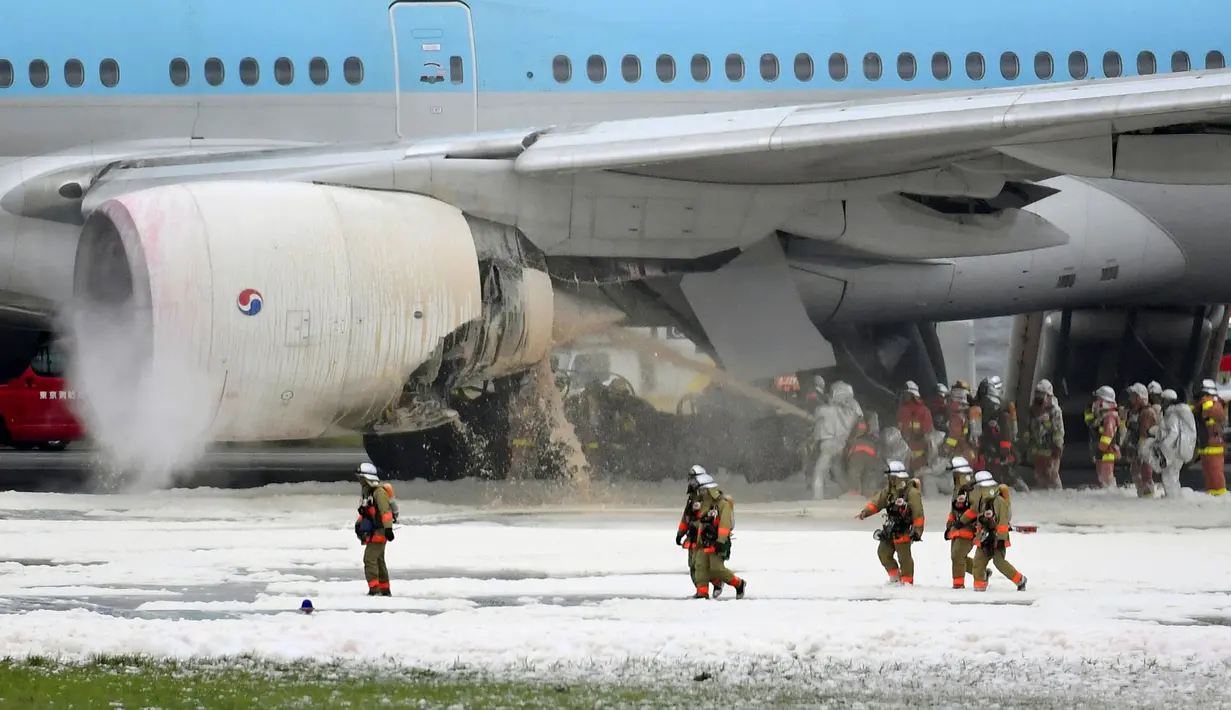 Petugas pemadam kebakaran menyemprotkan busa pada mesin pesawat Korean Air Lines di bandara Haneda di Tokyo, Jepang, (27/5). Insiden ini mendorong pemerintah untuk menutup sementara turun hub penerbangan tersibuk di Jepang. (Reuters/ Kyodo)