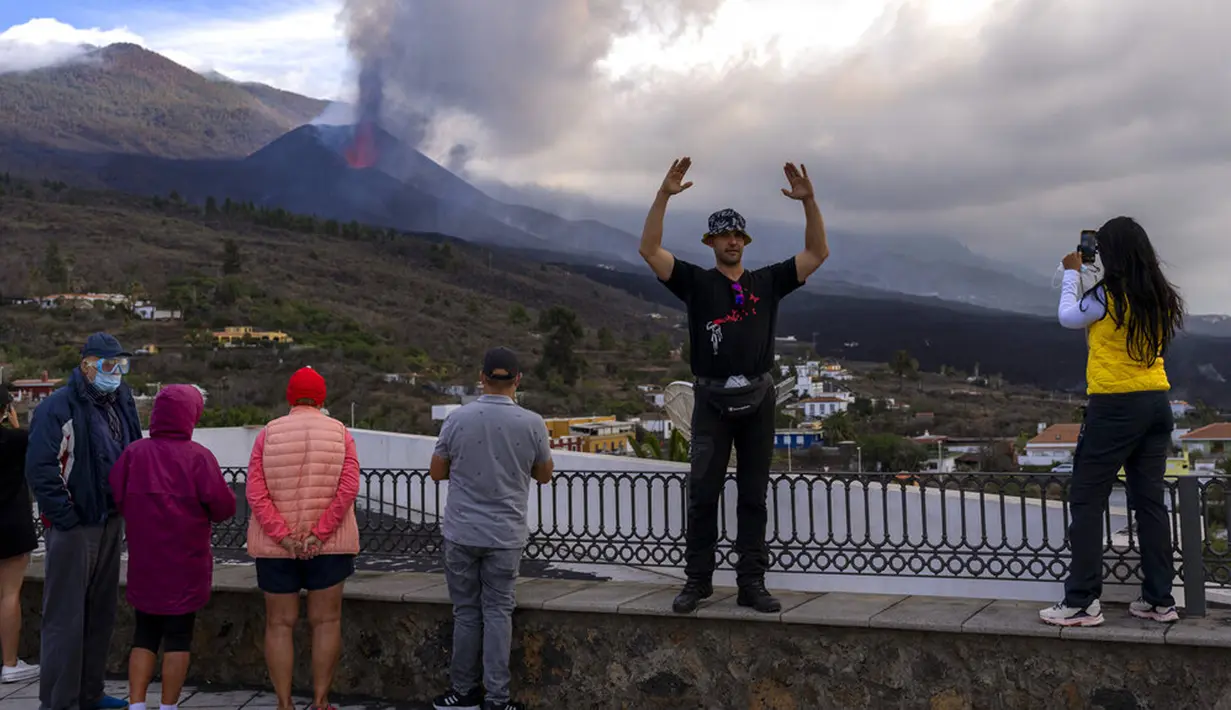 Wisatawan melihat dan mengambil foto gunung berapi yang meletus di Canary, Pulau La Palma, Spanyol, 26 Oktober 2021. Para pejabat mengatakan gunung berapi yang meletus selama lima minggu terakhir di Pulau La Palma lebih aktif dari sebelumnya. (AP Photo/Emilio Morenatti)