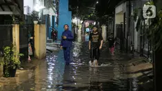 Warga berjalan menerjang banjir karena hujan di Jalan Shofa Marwah, Jakarta, Jumat (4/11/2022). Berdasarkan laporan Badan Penanggulangan Bencana Daerah (BPBD) DKI Jakarta yang diperbaharui pada pukul 18.00 WIB, terdapat 4 RT yang terendam banjir dengan ketinggian maksimal mencapai 50 Cm. (Liputan6.com/Faizal Fanani)