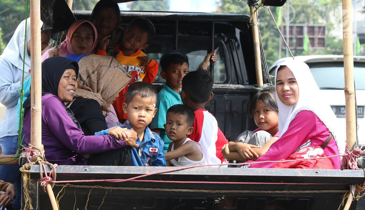 Sejumlah warga menaiki kendaraan bak terbuka saat bepergian libur lebaran menuju Kebun Binatang Ragunan di kawasan Jakarta, Minggu (9/6/2019). Warga memilih berpergian dengan mobil bak terbuka dan truk walau sangat membahayakan keselamatan mereka. (Liputan6.com/Herman Zakharia)