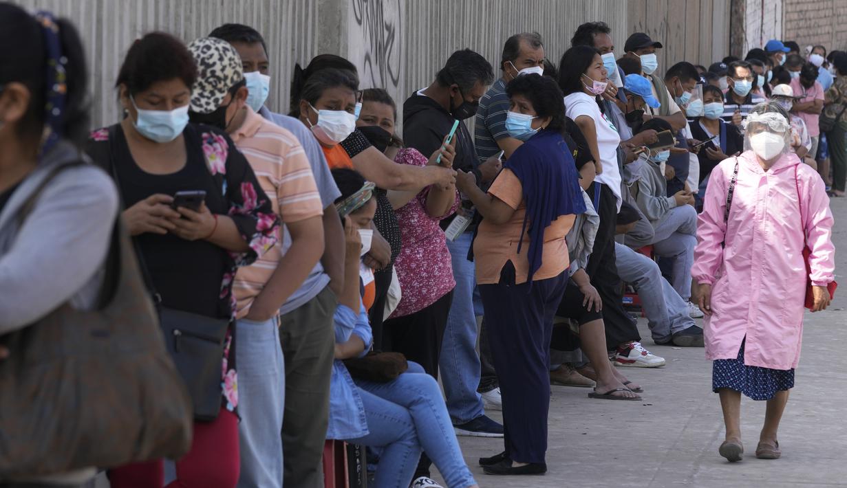 Seorang wanita mengenakan masker dan face shield melewati antrean orang yang menunggu tes PCR di Lima, Rabu (5/1/2022).Peru mengonfirmasi pada Selasa dimulainya gelombang ketiga infeksi virus corona di mana negara itu mencatat 309 kasus varian omicron yang sangat menular. (AP Photo/Martin Mejia)