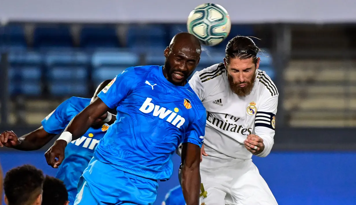 Bek Real Madrid, Sergio Ramos, bebrebut bola dengan bek Valencia, Eliaquim Mangala, pada laga lanjutan La Liga Spanyol pekan ke-29 di Stadion Alfredo, Stefano, Jumat  (19/6/2020) dini hari WIB. Real Madrid menang 3-0 atas Valencia. (AFP/Javier Soriano)