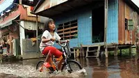 Seorang bocah melintasi banjir dengan menggunakan sepeda saat terjadi banjir di Ujung Tanah, Makassar. (ANTARA)